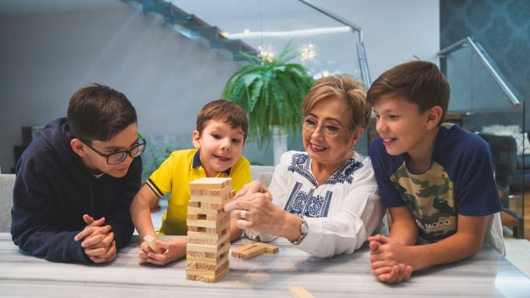A joyful family moment with grandma and grandsons playing Jenga indoors, capturing quality time together.