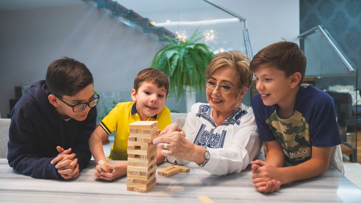 A joyful family moment with grandma and grandsons playing Jenga indoors, capturing quality time together.