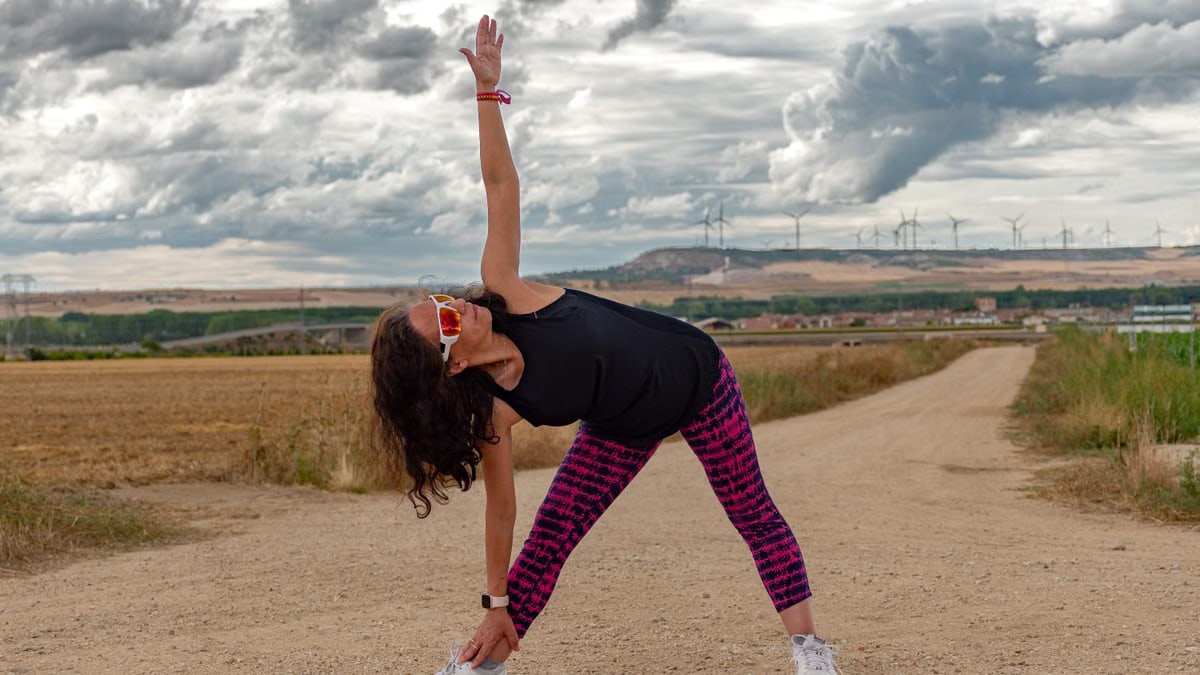Outdoor fitness scene of a woman stretching on a dirt path in Soto de Cerrato amidst scenic landscapes.